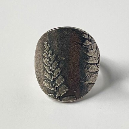 Bague ronde en argent 925 antiquité avec motif de feuille de fougère en relief et partie d'une feuille de fougère sur le côté droit.