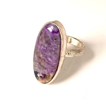 Bague de forme ovale en argent 925 avec une monture simple qui accompagne une pierre de charoïte.